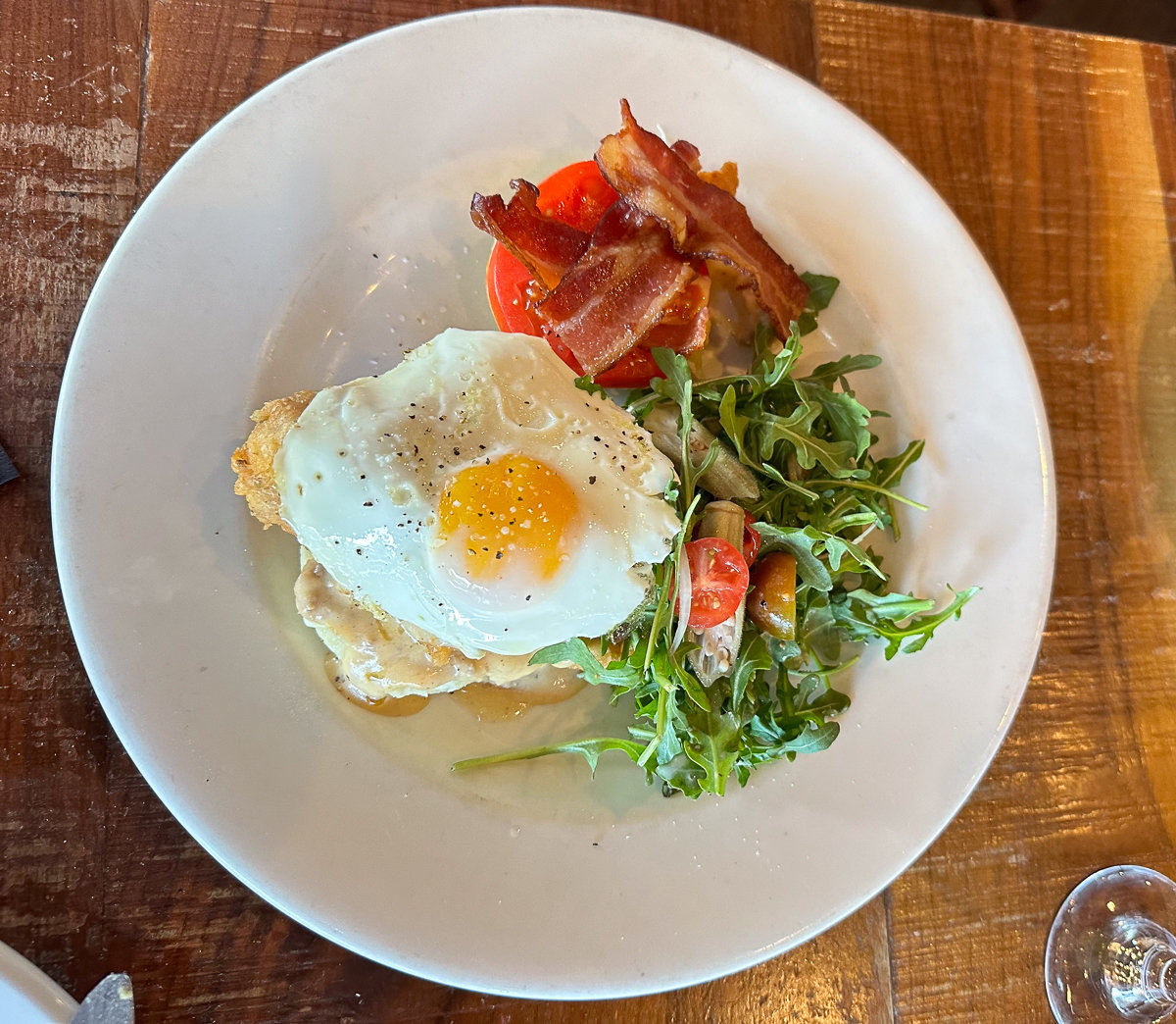 white plate with egg and salad with bacon